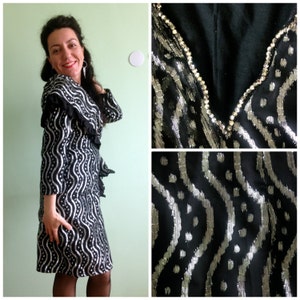 May include: A black and silver dress with a ruffled collar and a wavy pattern. The dress is adorned with rhinestones around the neckline.