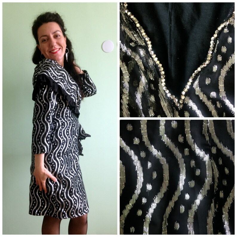 May include: A black and silver dress with a ruffled collar and a wavy pattern. The dress is adorned with rhinestones around the neckline.