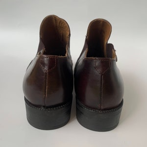 K&ouml;nnte beinhalten: Ein Paar braune Lederstiefeletten mit spitzer Zehenpartie und niedrigem Absatz. Die Stiefeletten haben einen Pull-on-Stil und ein glattes Lederfinish.