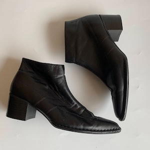 Könnte beinhalten: Ein Paar schwarze Leder-Stiefeletten mit spitzer Zehenpartie und Blockabsatz.