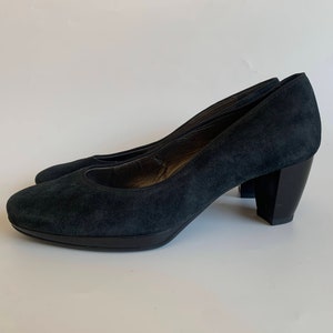 May include: A pair of dark blue suede pumps with a block heel. The heels are about 3 inches tall.