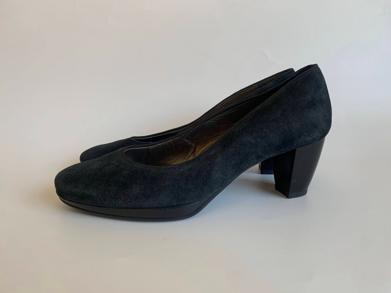 May include: A pair of dark blue suede pumps with a block heel. The heels are about 3 inches tall.