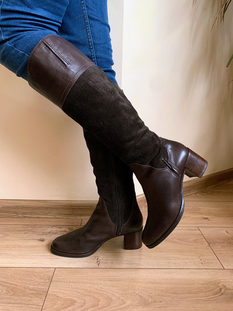 May include: Brown leather and suede knee-high boots with a block heel.
