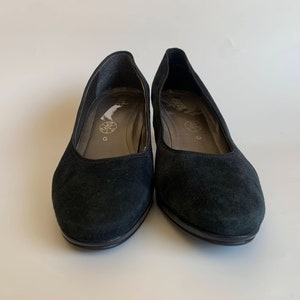 May include: A pair of black suede heeled shoes with a rounded toe.