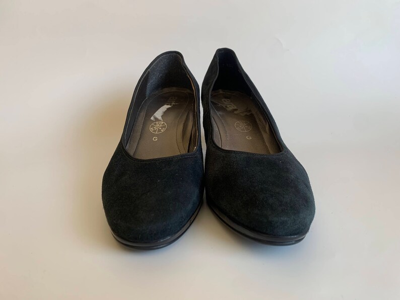 May include: A pair of black suede heeled shoes with a rounded toe.