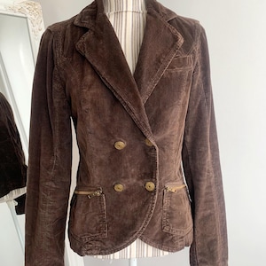 May include: A brown corduroy blazer with a double breasted closure and gold buttons. The blazer has two zippered pockets on the front.