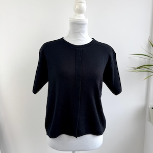 May include: A black short-sleeve sweater displayed on a white mannequin. The sweater has a crew neck and a vertical seam down the front. The garment is made of a soft, dark material.