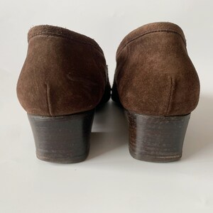 May include: A pair of brown suede heeled shoes with a low block heel.