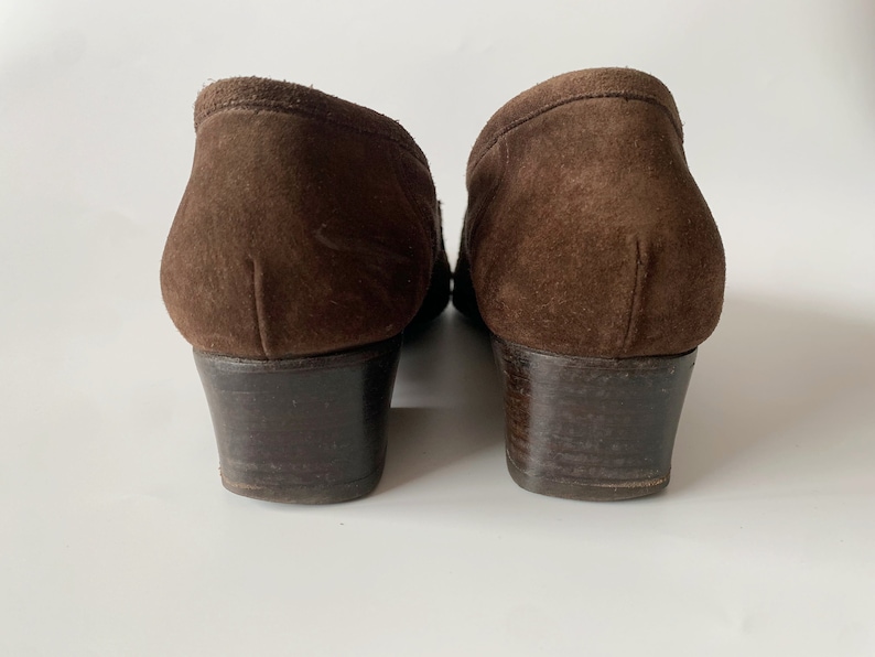 May include: A pair of brown suede heeled shoes with a low block heel.