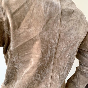 May include: A brown suede jacket with a zipper closure and long sleeves.