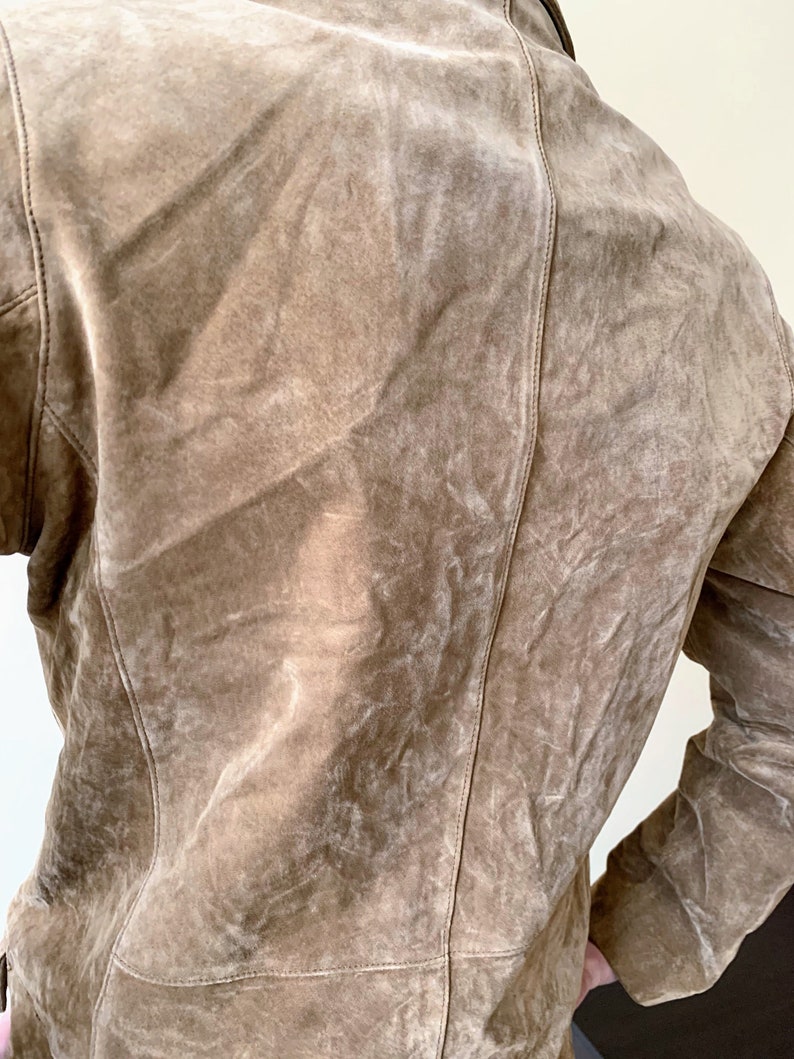 May include: A brown suede jacket with a zipper closure and long sleeves.