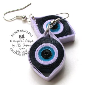 May include: A pair of purple and black evil eye earrings made with paper quilling. The earrings are handmade and feature a silver hook.