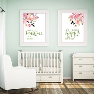 May include: Two white framed prints with pink floral designs and green text. The left print says "You are my sunshine, my only sunshine." The right print says "You make me happy when skies are grey."