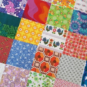 Op de afbeelding: Een patchworkquilt bestaande uit diverse stoffen vierkanten. De vierkanten tonen diverse bloemen-, geometrische en abstracte patronen in levendige kleuren zoals oranje, groen, paars en blauw. De quilt heeft een vintage esthetiek.