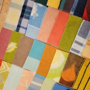 May include: A collection of rectangular fabric swatches arranged in a grid pattern. The swatches feature a variety of colors including yellow, orange, green, blue, and pink, with diverse textures and patterns such as plaid, stripes, and solid tones.