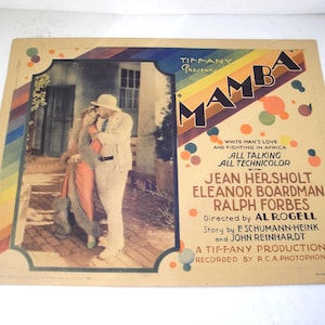 May include: A vintage lobby card for the film Mamba, featuring a scene of two people in light-colored clothing. The poster includes the text Tiffany Presents Mamba, White Man's Love and Fighting in Africa, All Talking All Technicolor.