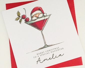 May include: A Christmas card featuring a Santa Claus in a martini glass design. The card has a red and white color scheme, with the text "MERRY CHRISTMAS TO A SPECIAL DAUGHTER" and the name "Amelia".