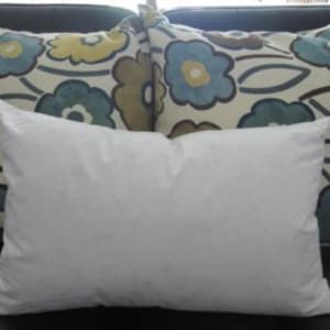 May include: A white down pillow, a standard size pillow, for sleeping or resting on a couch.