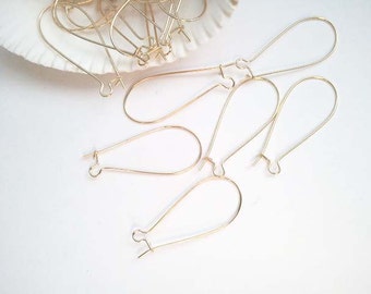 May include: A set of gold-toned earring findings, also known as ear wires, for jewelry making. The findings are shaped like a teardrop and have a loop at the top for attaching earrings.