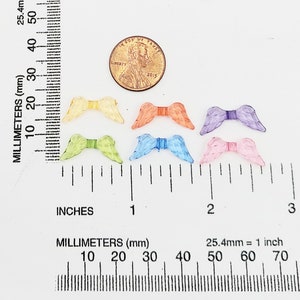 May include: Six pairs of colorful angel wings made of plastic. The wings are about 1 inch wide and 1 inch long. The wings are in the colors of yellow, green, orange, blue, purple, and pink.