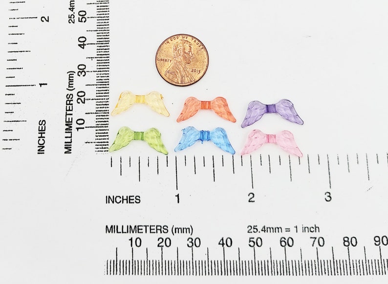 May include: Six pairs of colorful angel wings made of plastic. The wings are about 1 inch wide and 1 inch long. The wings are in the colors of yellow, green, orange, blue, purple, and pink.