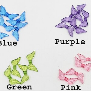 May include: Assortment of plastic angel wings in blue, green, purple, and pink colors. The wings are small and delicate, perfect for crafting or decorating.