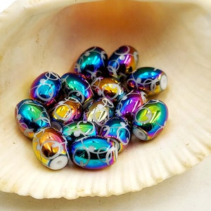 May include: A group of iridescent oval beads with white swirl designs. The beads are arranged in a seashell.