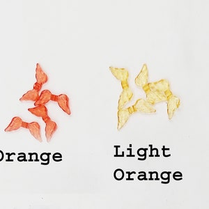 May include: Two sets of plastic angel wings, one set is orange and the other is light orange.