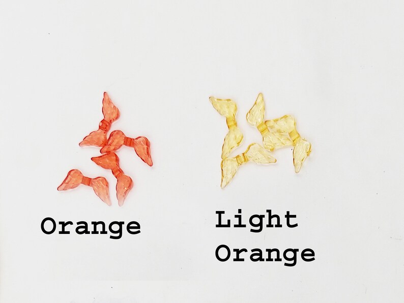 May include: Two sets of plastic angel wings, one set is orange and the other is light orange.