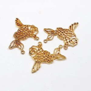 May include: Three gold-colored metal fish charms with intricate cut-out designs. The charms are perfect for jewelry making, scrapbooking, and other craft projects.