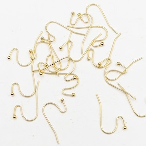 May include: A pile of gold-colored earring hooks with small round balls at the end of each hook.