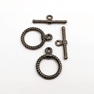 May include: Three silver-toned metal toggle clasps with a rope-like design. Two clasps are circular and one is a bar-shaped clasp.