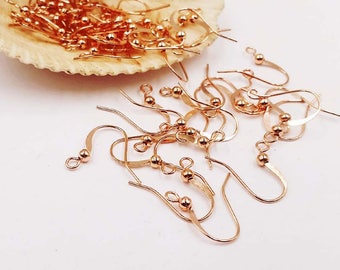 May include: A close-up of a pile of gold-toned earring hooks. The hooks are made of metal and have a small ball at the top. They are ideal for making earrings.