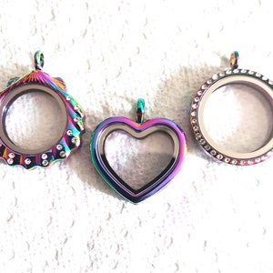 May include: Three iridescent charm pendants with clear glass inserts. The pendants are shaped like a shell, a heart, and a circle. Each pendant is decorated with clear rhinestones.
