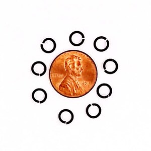 May include: A copper penny surrounded by ten black, open-ended rings. The penny features a profile of a man's head and the year 2011. The rings are evenly spaced around the coin against a white background.
