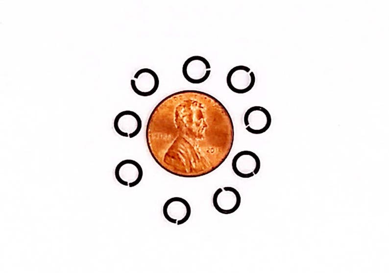 May include: A copper penny surrounded by ten black, open-ended rings. The penny features a profile of a man's head and the year 2011. The rings are evenly spaced around the coin against a white background.