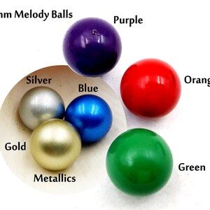 May include: Six 16mm melody balls in a variety of colors, including purple, red, blue, green, silver, and gold. The balls are arranged in a circle on a white surface.