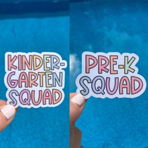 May include: Two colorful vinyl stickers with the text "Kindergarten Squad" and "Pre-K Squad". The stickers have a white background and are outlined in black.