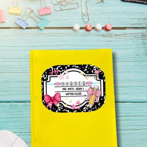 May include: A yellow writing folder with a decorative label. The label features the name "HARPER", the text "MRS. SMITH - GRADE 1", and "WRITING FOLDER". The label has a black and white pattern, pink bows, hearts, and a pencil illustration.