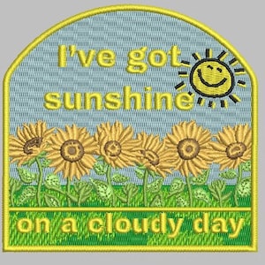 May include: Embroidered patch with a blue background and yellow text that reads "I've got sunshine on a cloudy day". The patch features a yellow smiling sun and a row of yellow sunflowers.