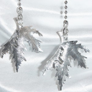 May include: Two silver leaf-shaped pull chains with a beaded chain attached to each.