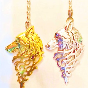 May include: Two pendant necklaces featuring wolf head designs. One is gold-toned, the other silver-toned. Both pendants have intricate cut-out details and are suspended from delicate chains. The wolf heads are in profile, with detailed features.