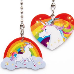May include: Two whimsical unicorn charms, one heart-shaped and one rainbow-shaped, suspended by silver chains. The charms feature a white unicorn with a colorful mane and tail, set against a rainbow background. The heart-shaped charm has a red border.