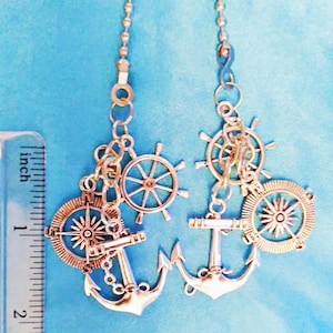 May include: Two silver charm necklaces with nautical themes. Each necklace features a silver anchor, compass, and ship's wheel charm.