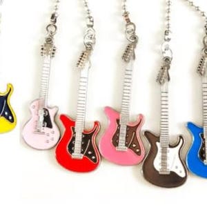 May include: A collection of colorful guitar-shaped charms. Each charm features a different color, including orange, yellow, pink, red, brown, blue, and white. The charms are attached to silver-colored chains.
