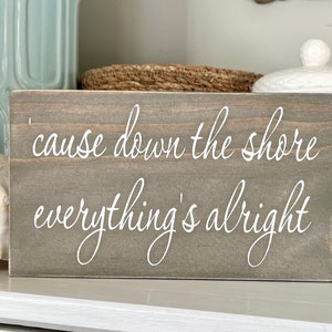 May include: A gray wooden sign with white text that reads "cause down the shore everything's alright".