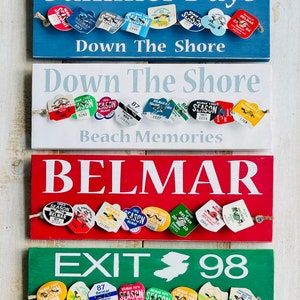 May include: Four rectangular wooden signs with text and attached vintage-style tags. The signs are blue, white, red, and green, with phrases like "Summer Days" and "Belmar." The tags have various colors and text, including "Season" and numbers.