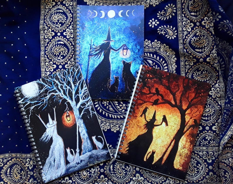 May include: Three spiral-bound notebooks with witch-themed illustrations. One features a witch with a lantern under a moonlit sky, another shows a witch and cats under a tree, and the third depicts a witch with crows under a sunset.