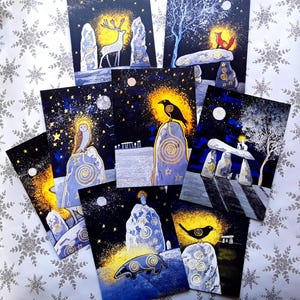 May include: A collection of art prints featuring celestial and nature-inspired designs. Each print showcases a night sky with stars, a full moon, and various animals like a deer, fox, owl, and badger, along with standing stones. The color palette includes blues, golds, and whites.