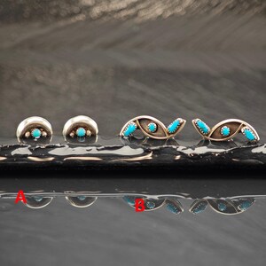 May include: Two pairs of silver earrings featuring bright blue turquoise stones. Pair A consists of two crescent-shaped studs with a single central stone. Pair B consists of two elongated, curved studs, each set with three small turquoise stones.
